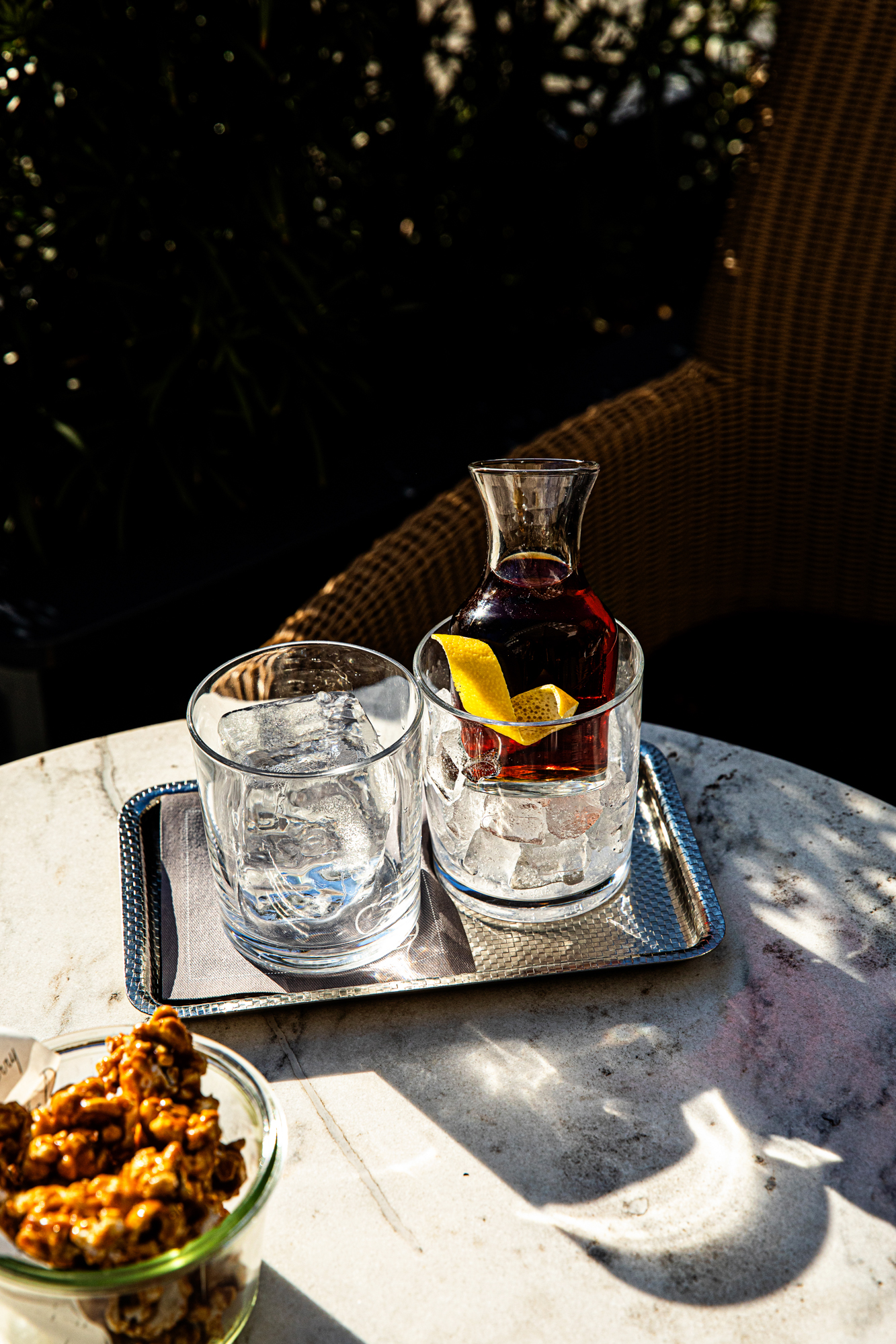Cocktails on a marble table in dappled sun at The Dewberry Charleston